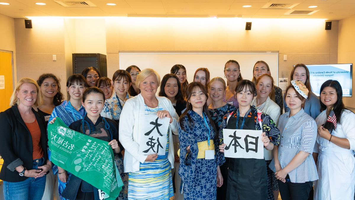 Large group of women posing with various signs.