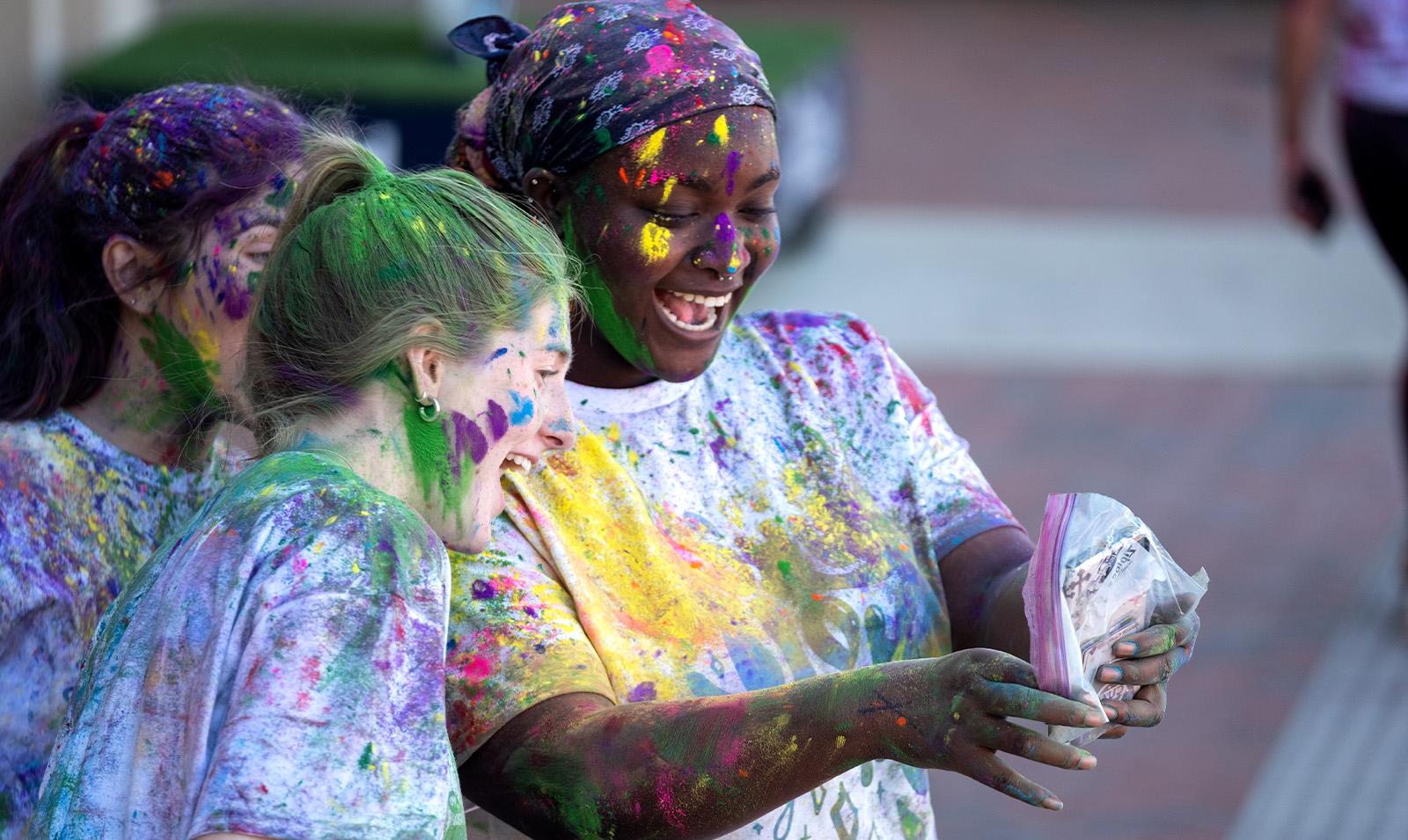 Two students covered in paint celebrating Holi.