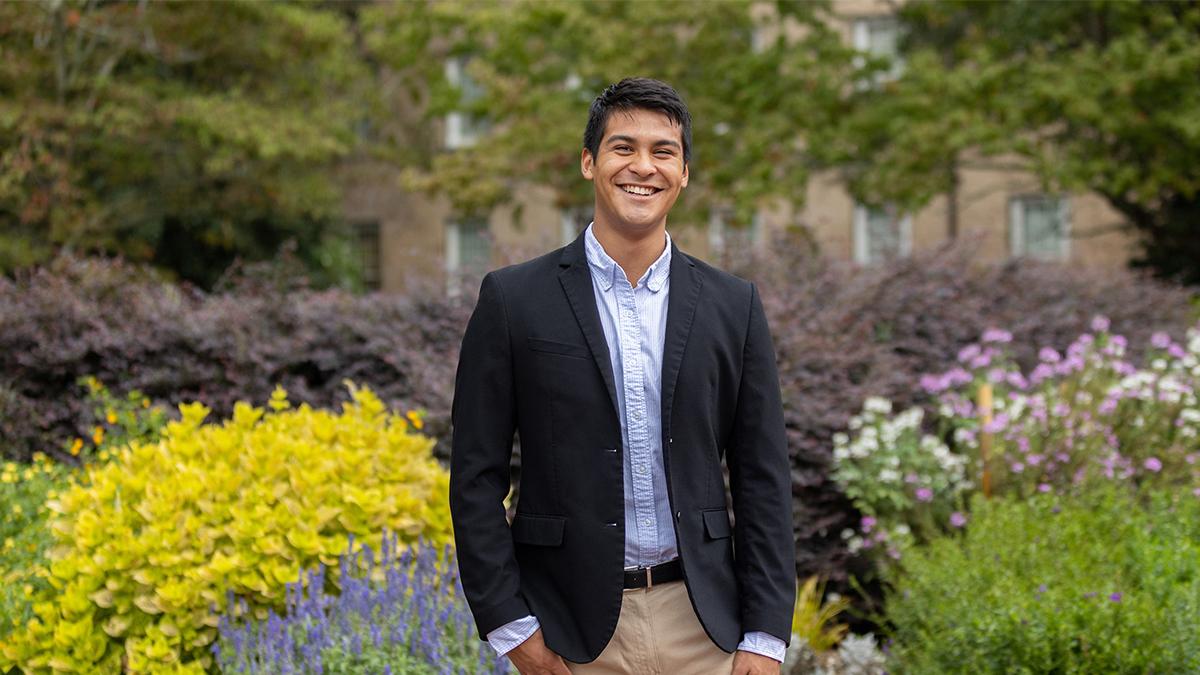 Gustavo Gonzales wearing suit in front of plants at the botanical garden.