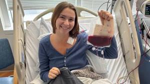 Samantha Lewis holding container of her own blood in hospital bed.